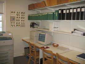 Photo of desk with shelves above holding numerous notebooks